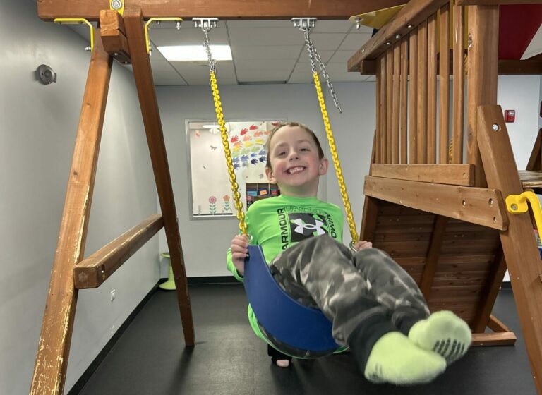a very happy child is swinging on our playground and smiling brightly!